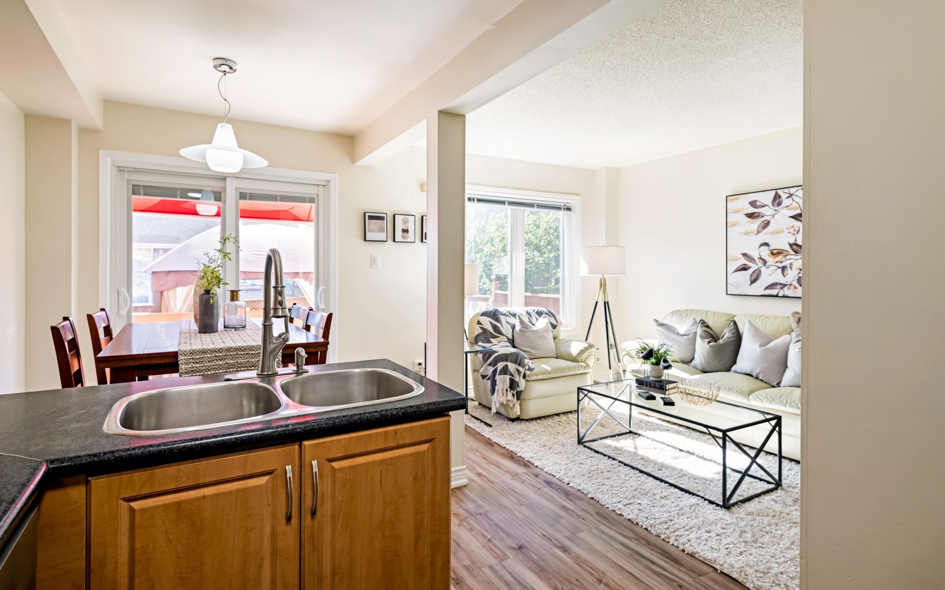 A kitchen with a sink and a sliding glass door leading to a living room.