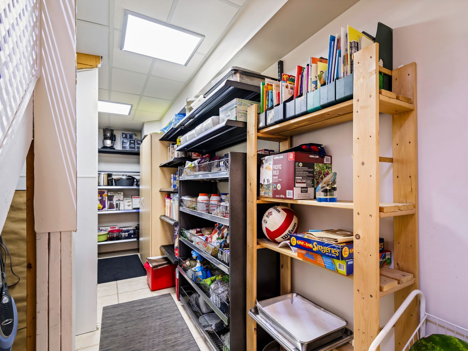 A walk in pantry with wooden shelves filled with lots of items.
