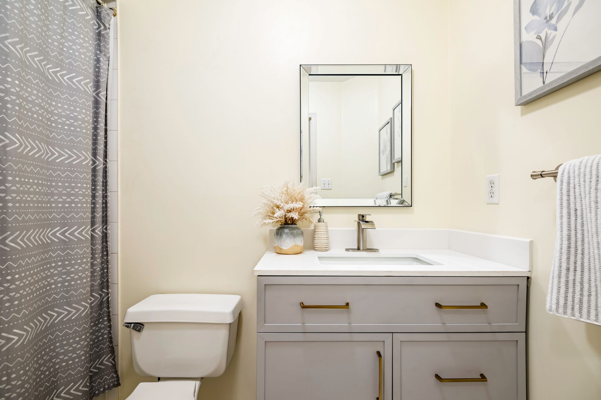 A bathroom with a toilet , sink , mirror and shower curtain.