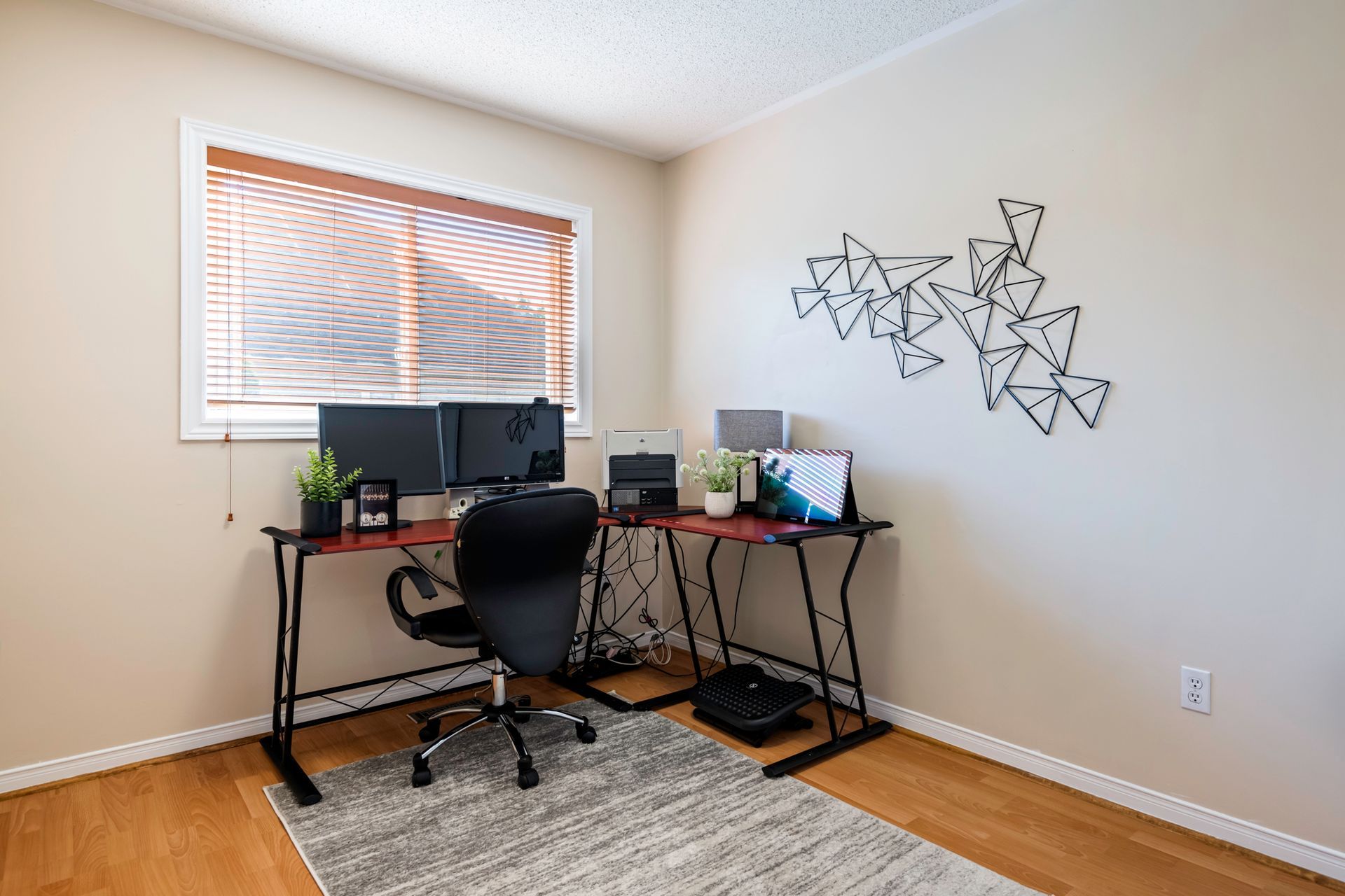 A home office with a desk , chair , computer and laptop.