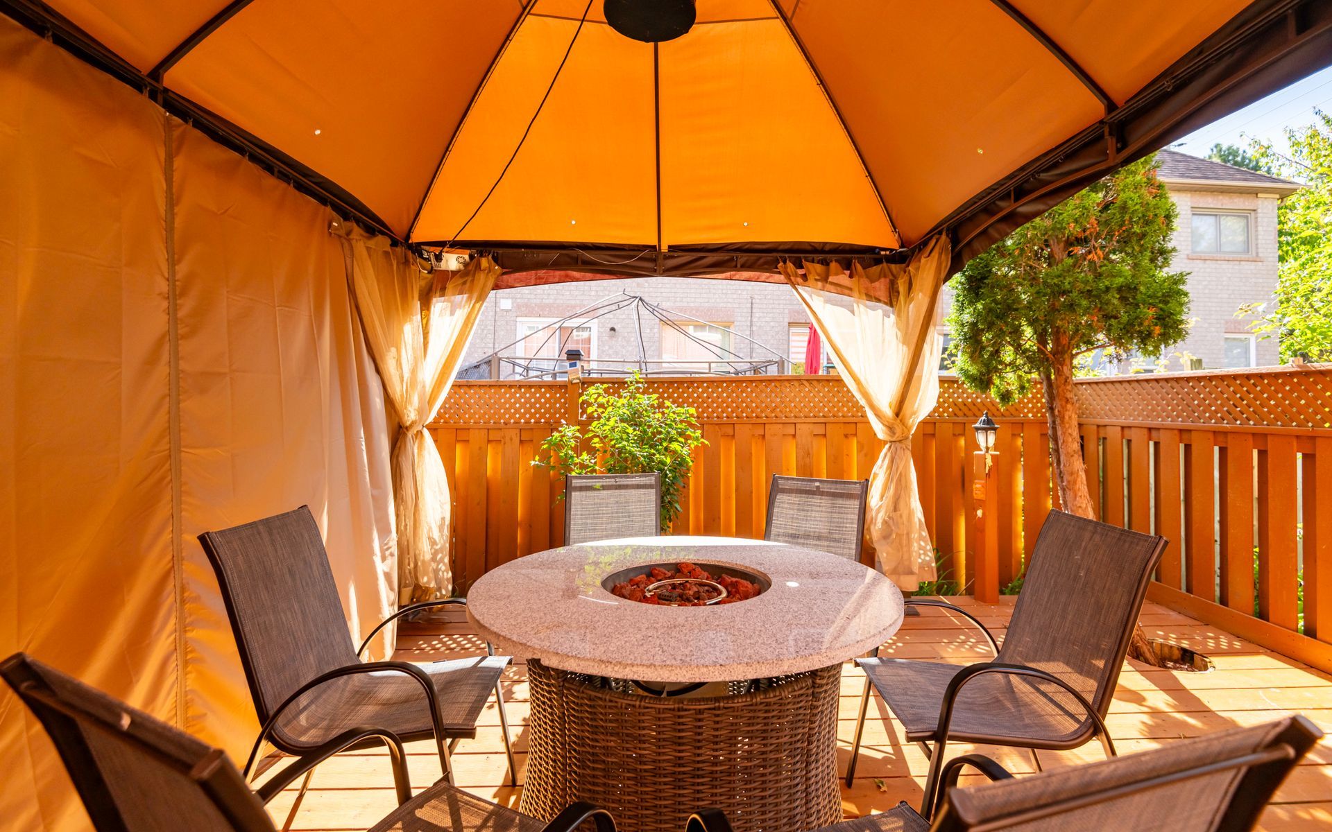 A gazebo with a fire pit and a table and chairs underneath it.