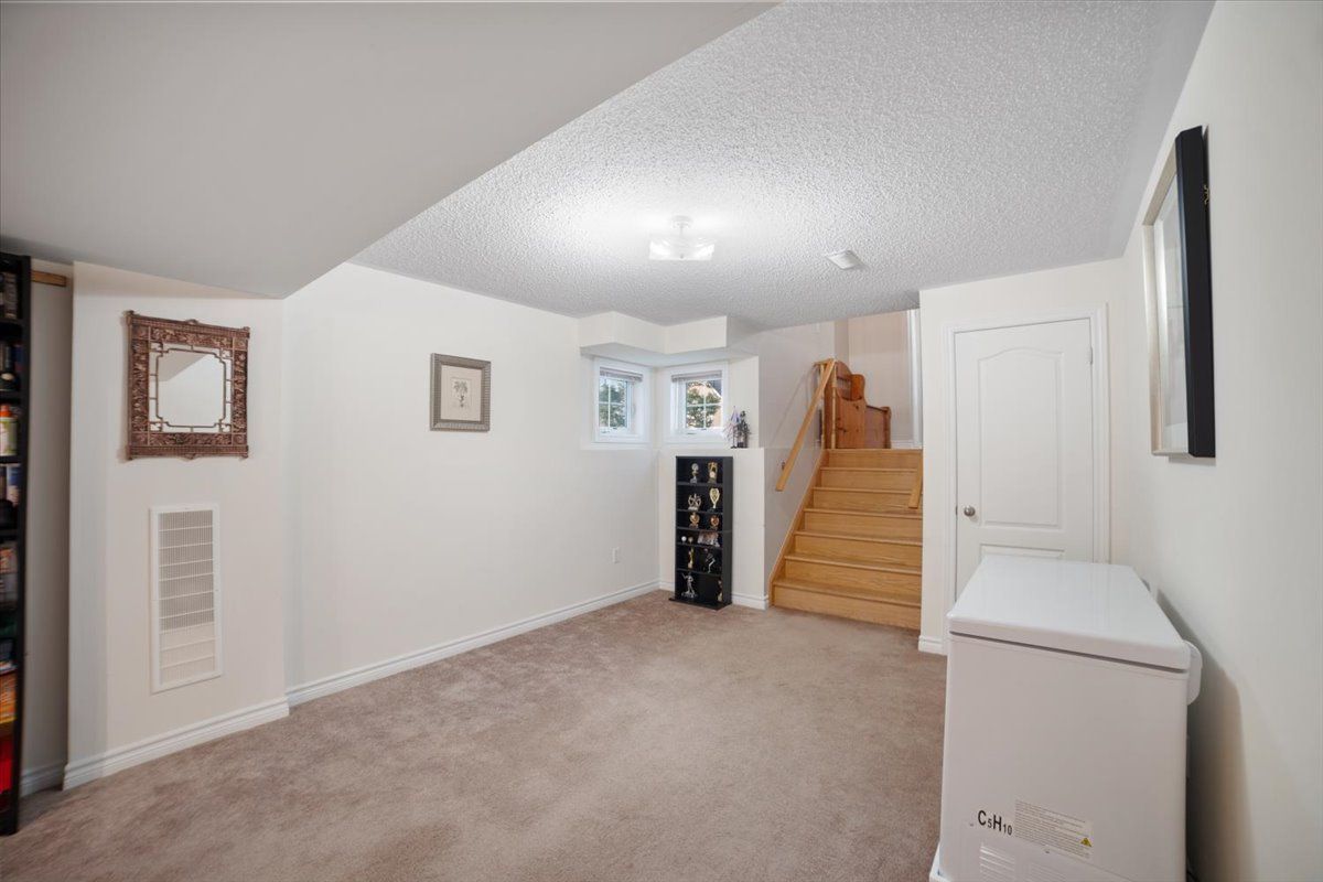 A basement with stairs and a refrigerator in it.