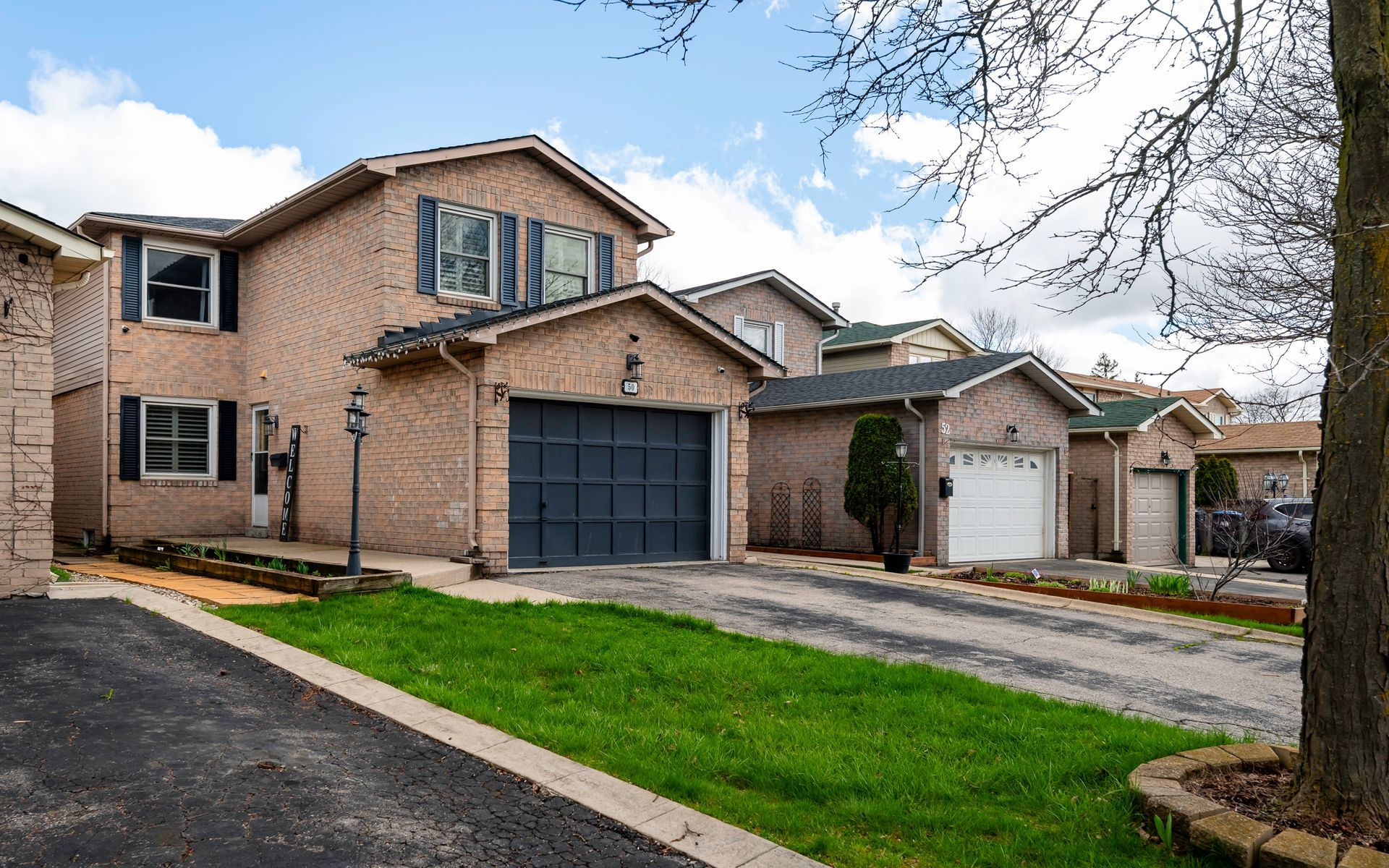 A large brick house with two garages and a large lawn in front of it.