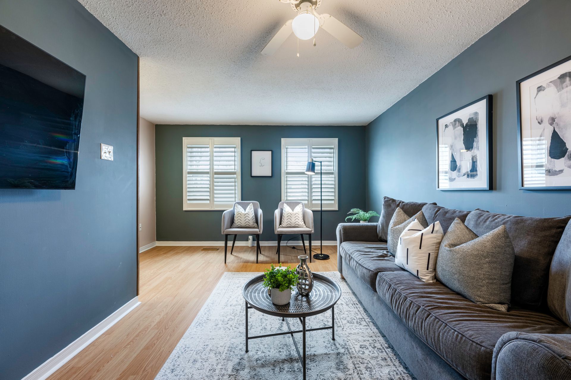 A living room with a couch , chairs and a ceiling fan