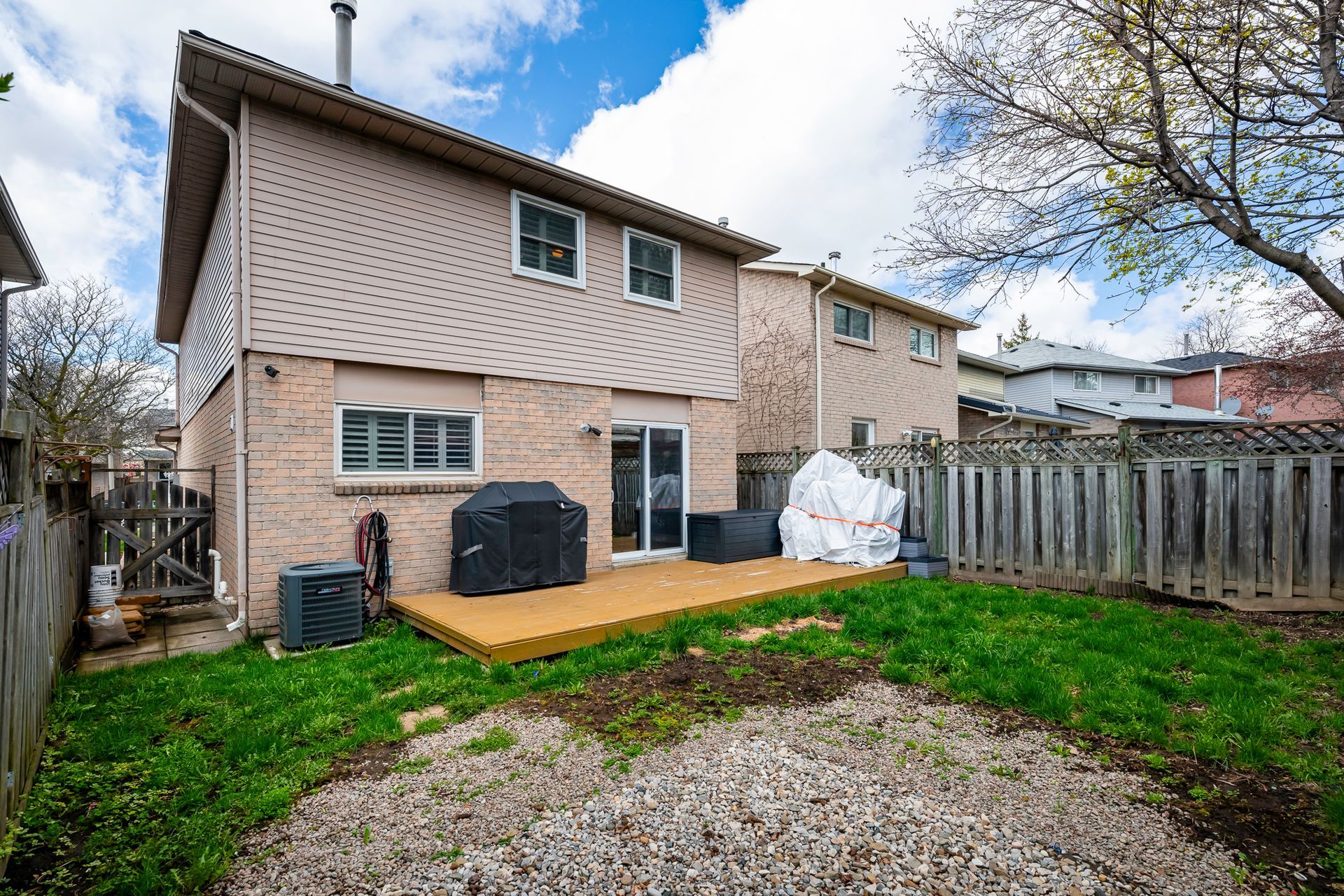 The backyard of a house with a deck and a fence.