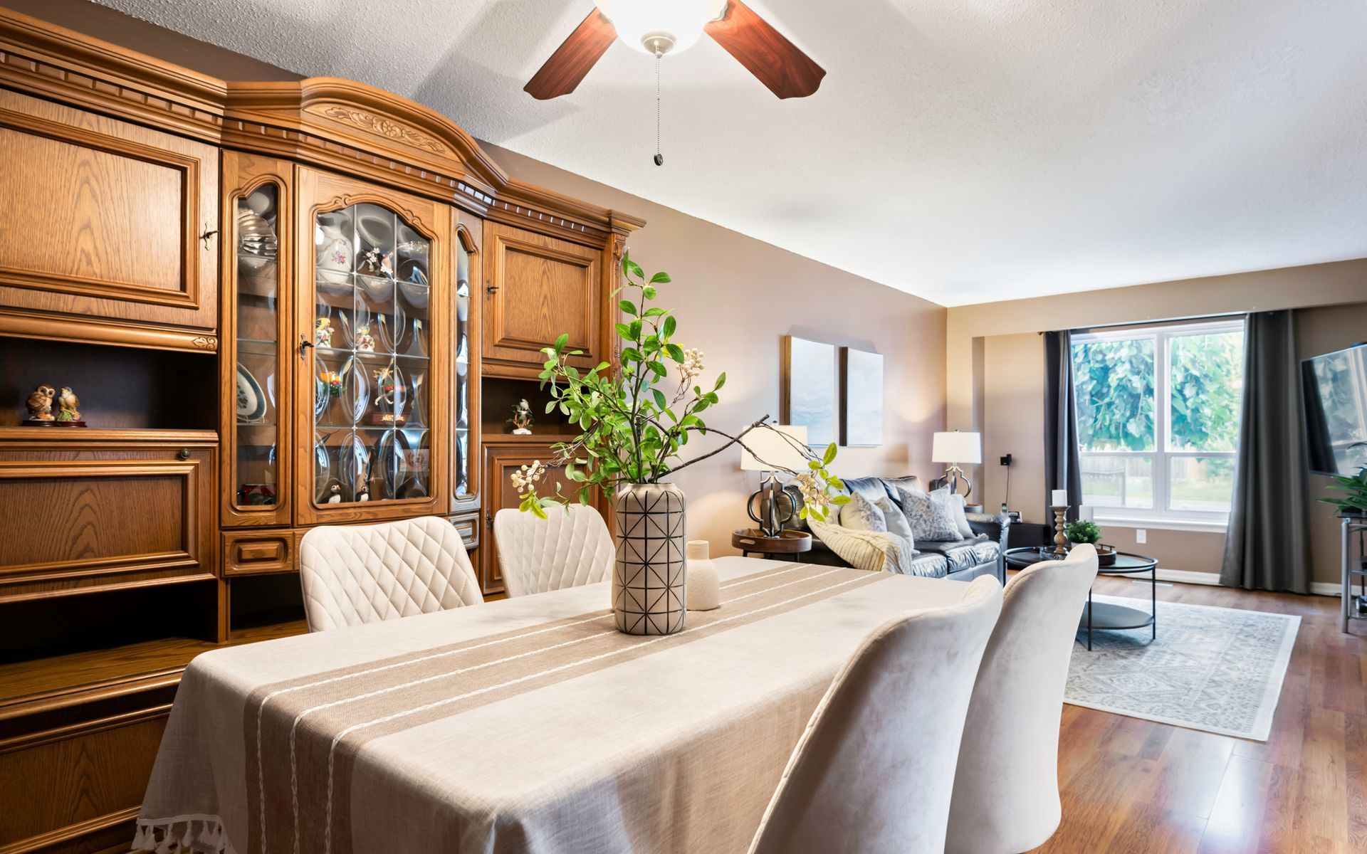 A dining room table and chairs in a living room with a ceiling fan.