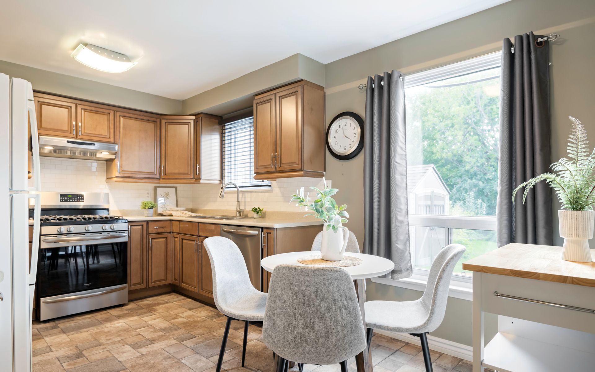 A kitchen with a table and chairs and a clock on the wall.