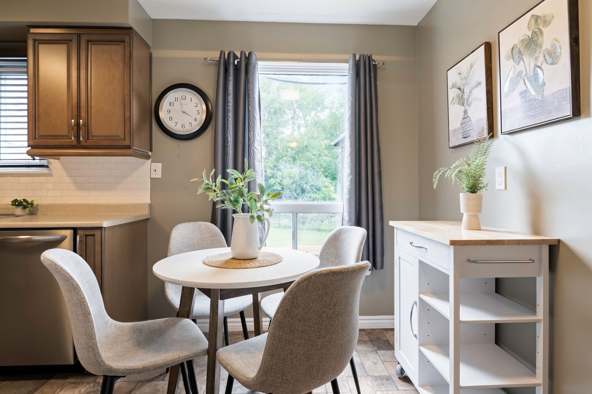 A kitchen with a table and chairs and a clock on the wall.