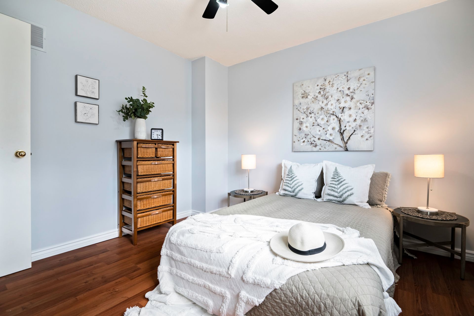 A bedroom with a bed , dresser , lamp and a ceiling fan.