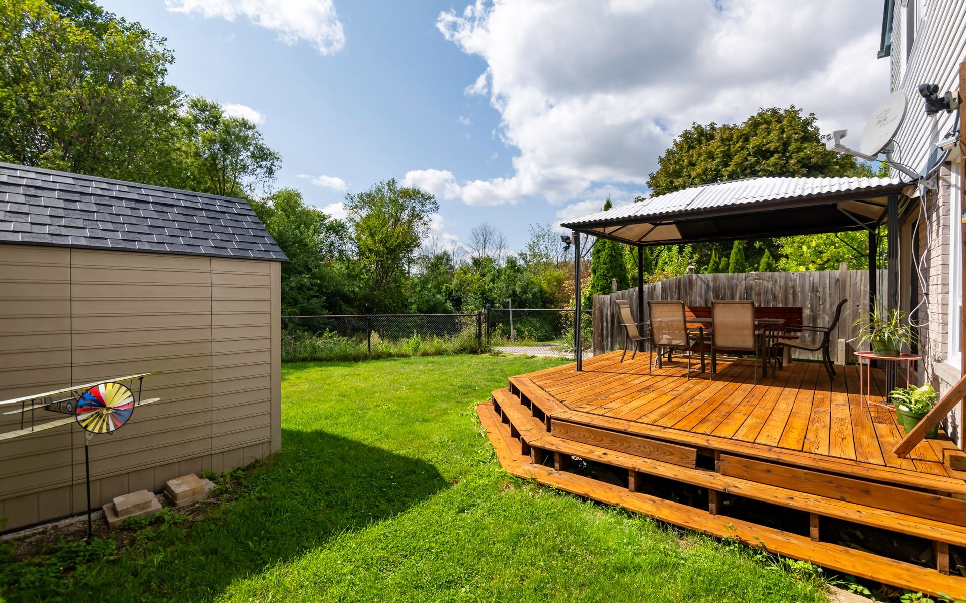 A backyard with a wooden deck and a gazebo.