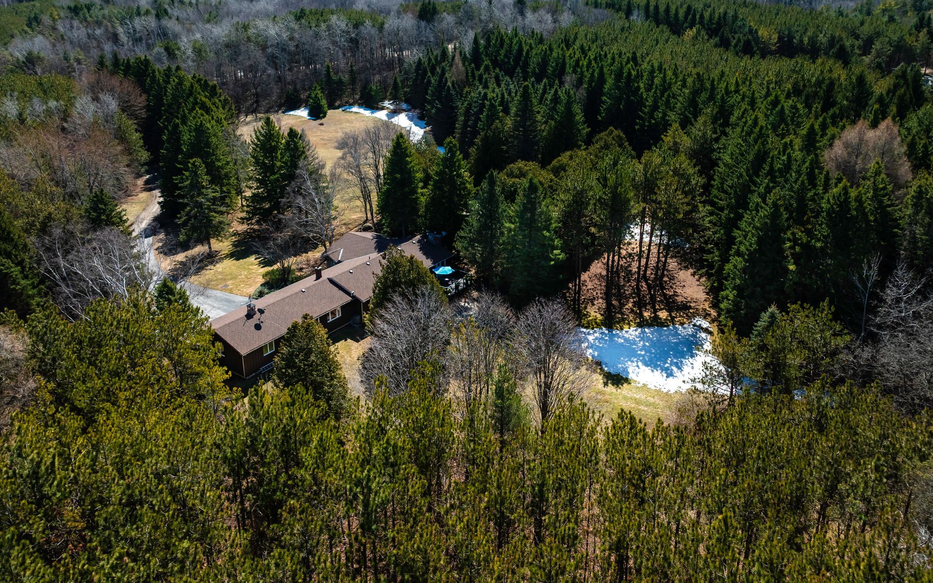 An aerial view of a house in the middle of a forest surrounded by trees.