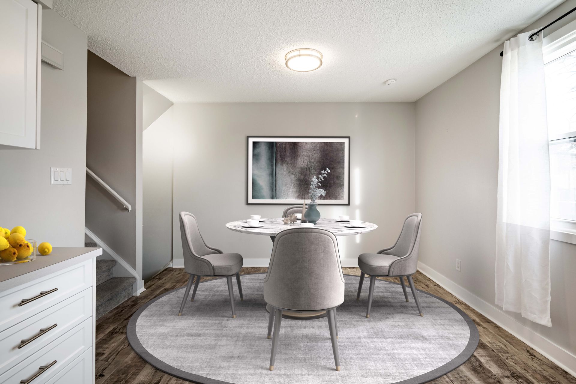 A dining room with a table and chairs and a picture on the wall.