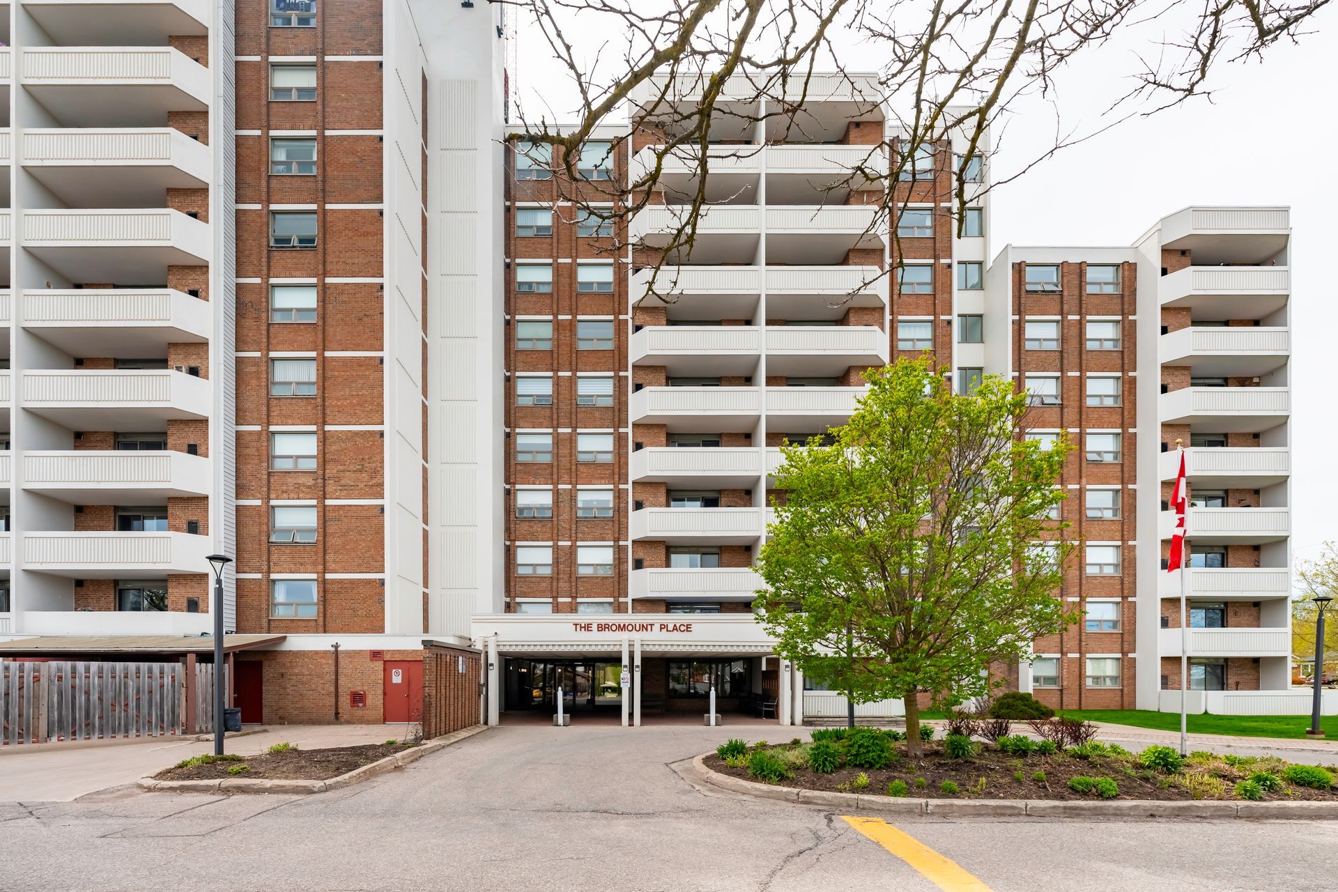 A large brick building with a lot of balconies and a tree in front of it.