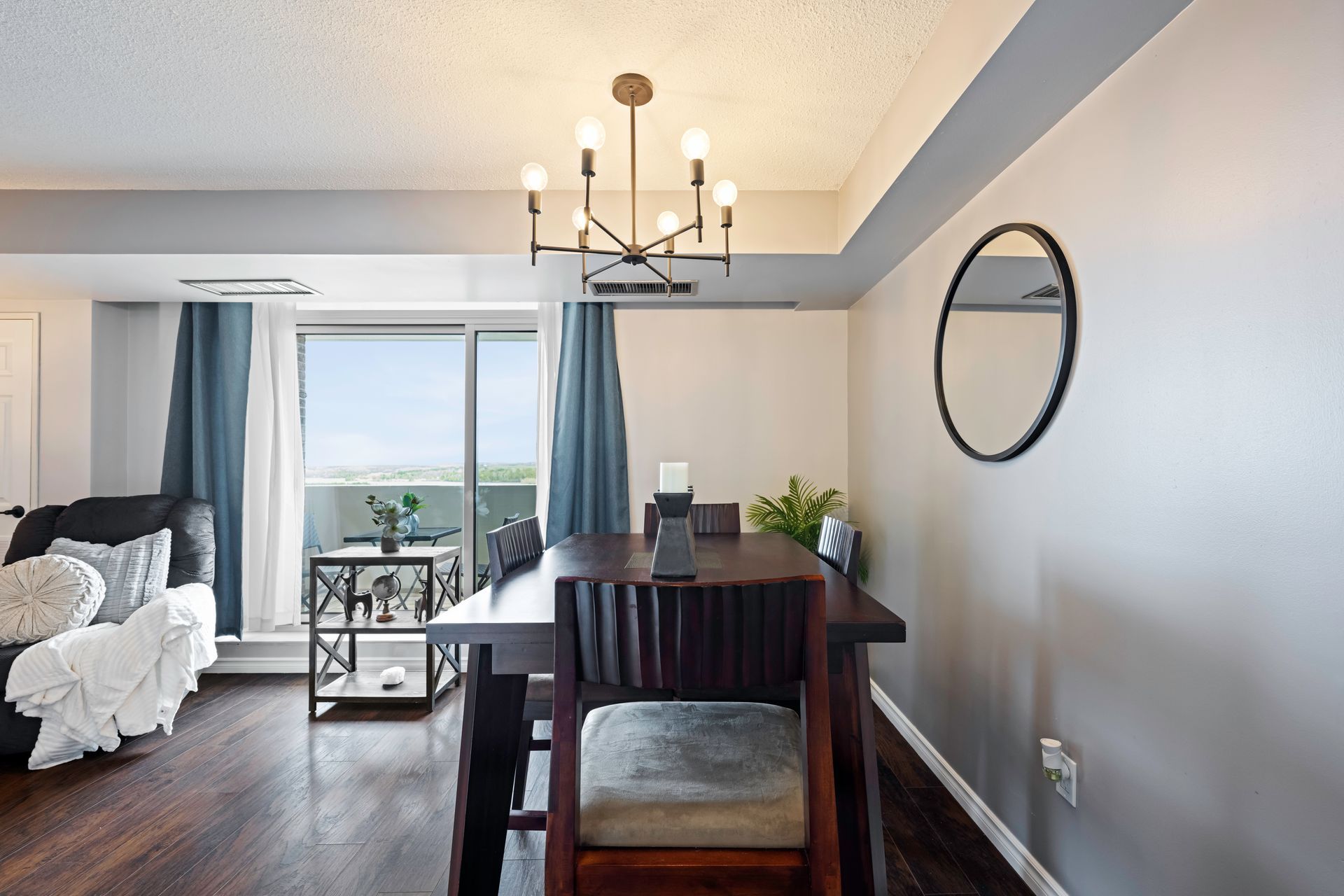 A dining room with a table and chairs and a mirror on the wall.