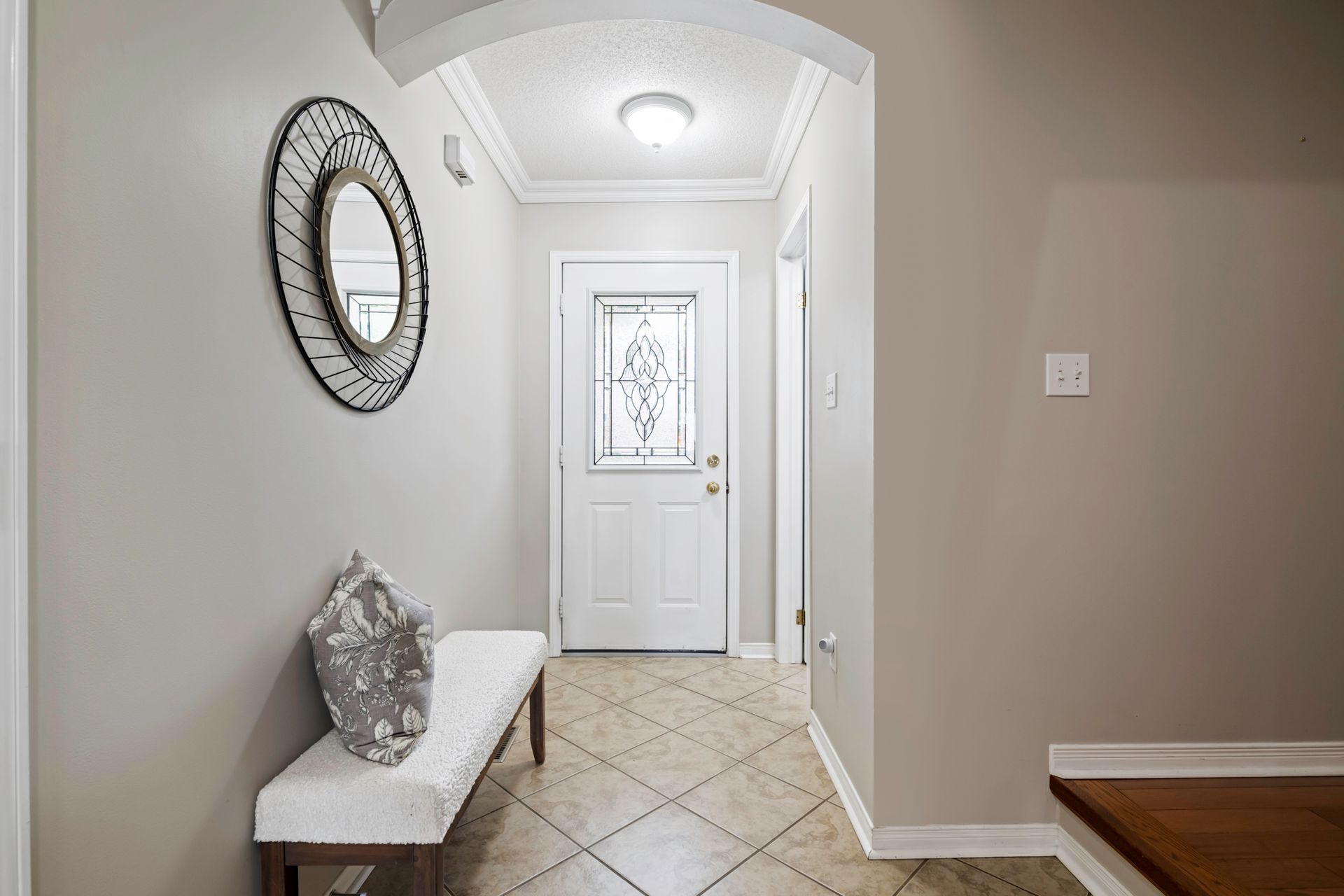A hallway with a bench and a mirror on the wall.