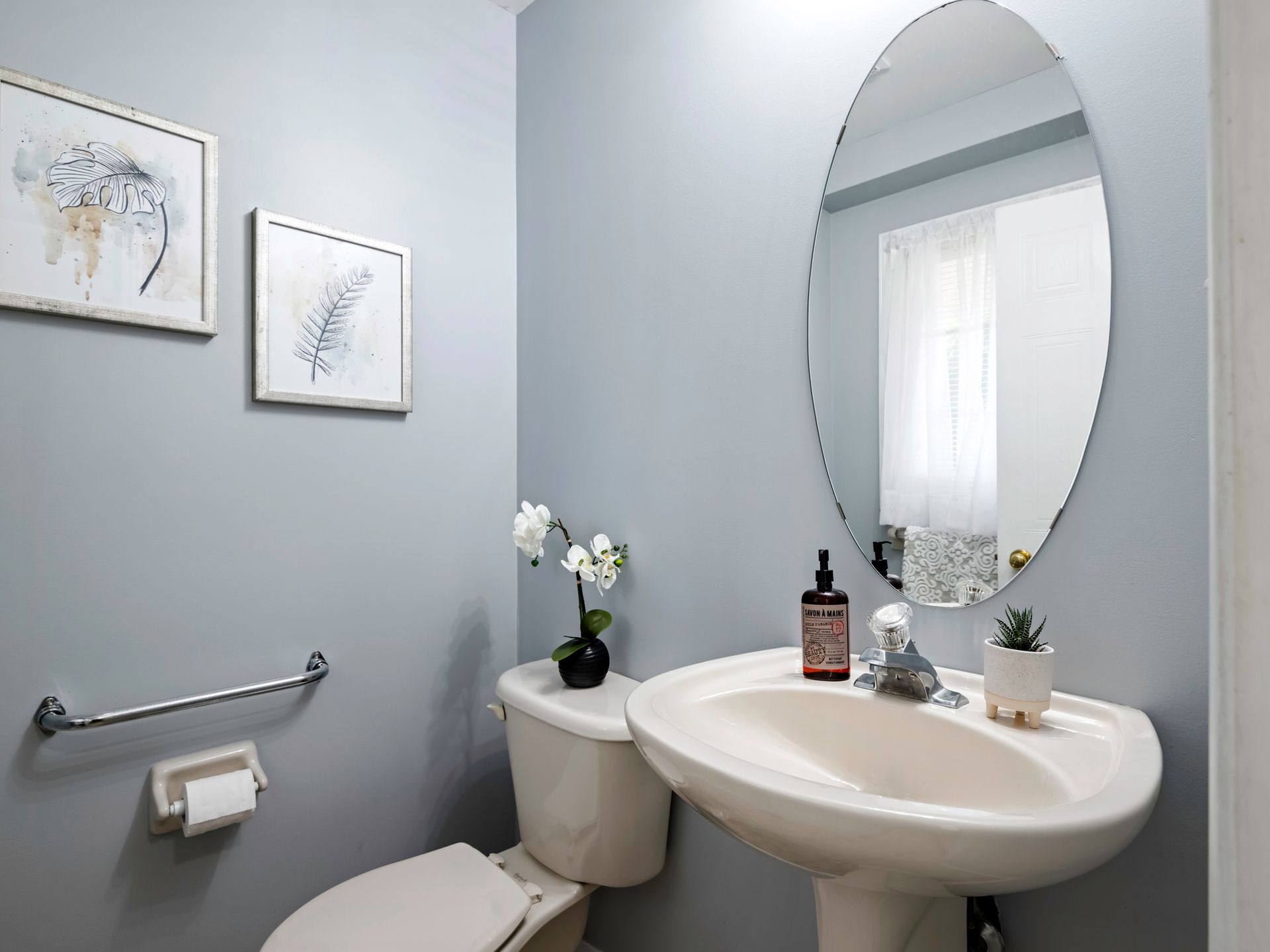 A bathroom with a toilet , sink and mirror.
