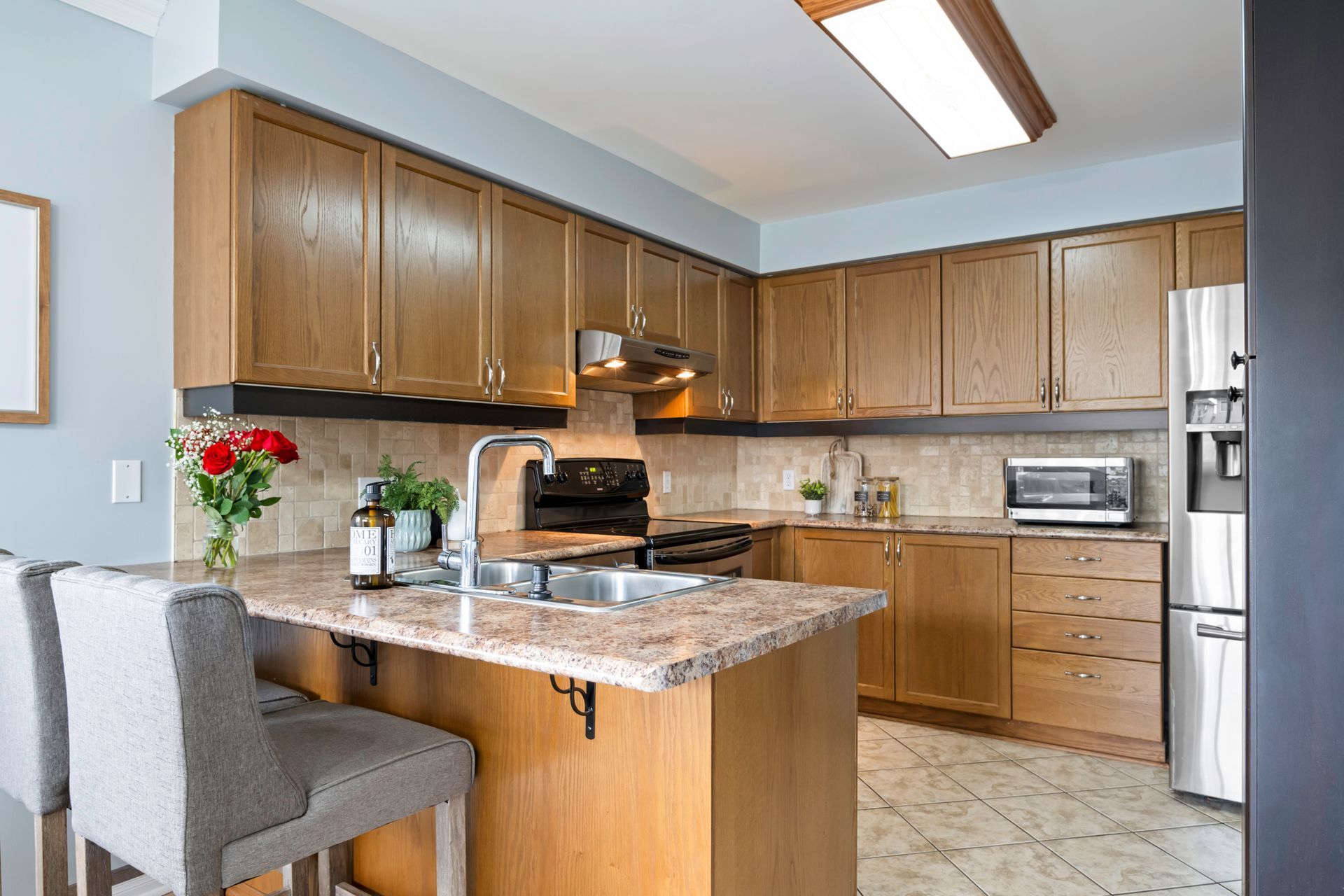 A kitchen with wooden cabinets , granite counter tops , stainless steel appliances , and a large island.