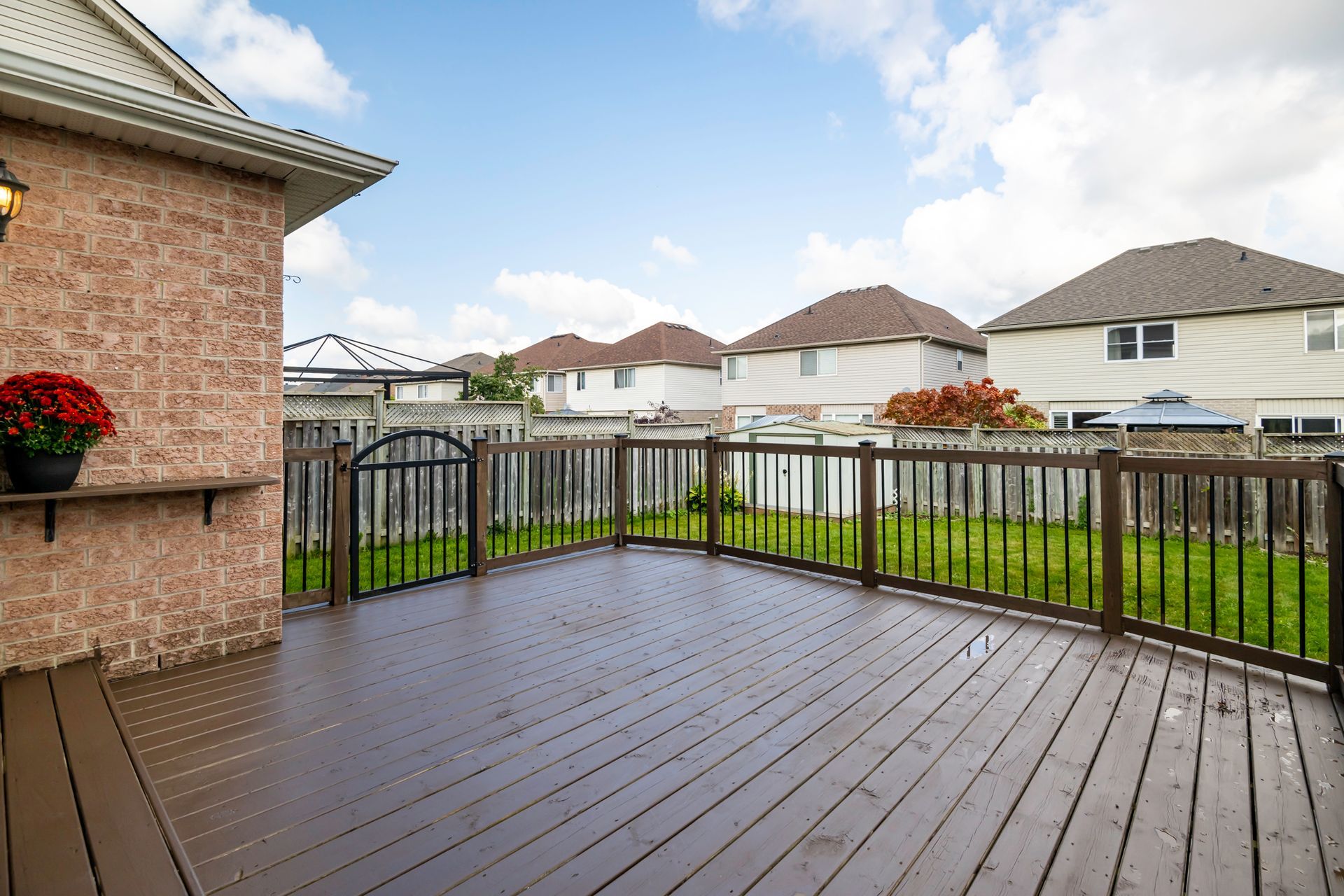 A large wooden deck with a metal railing in front of a house.