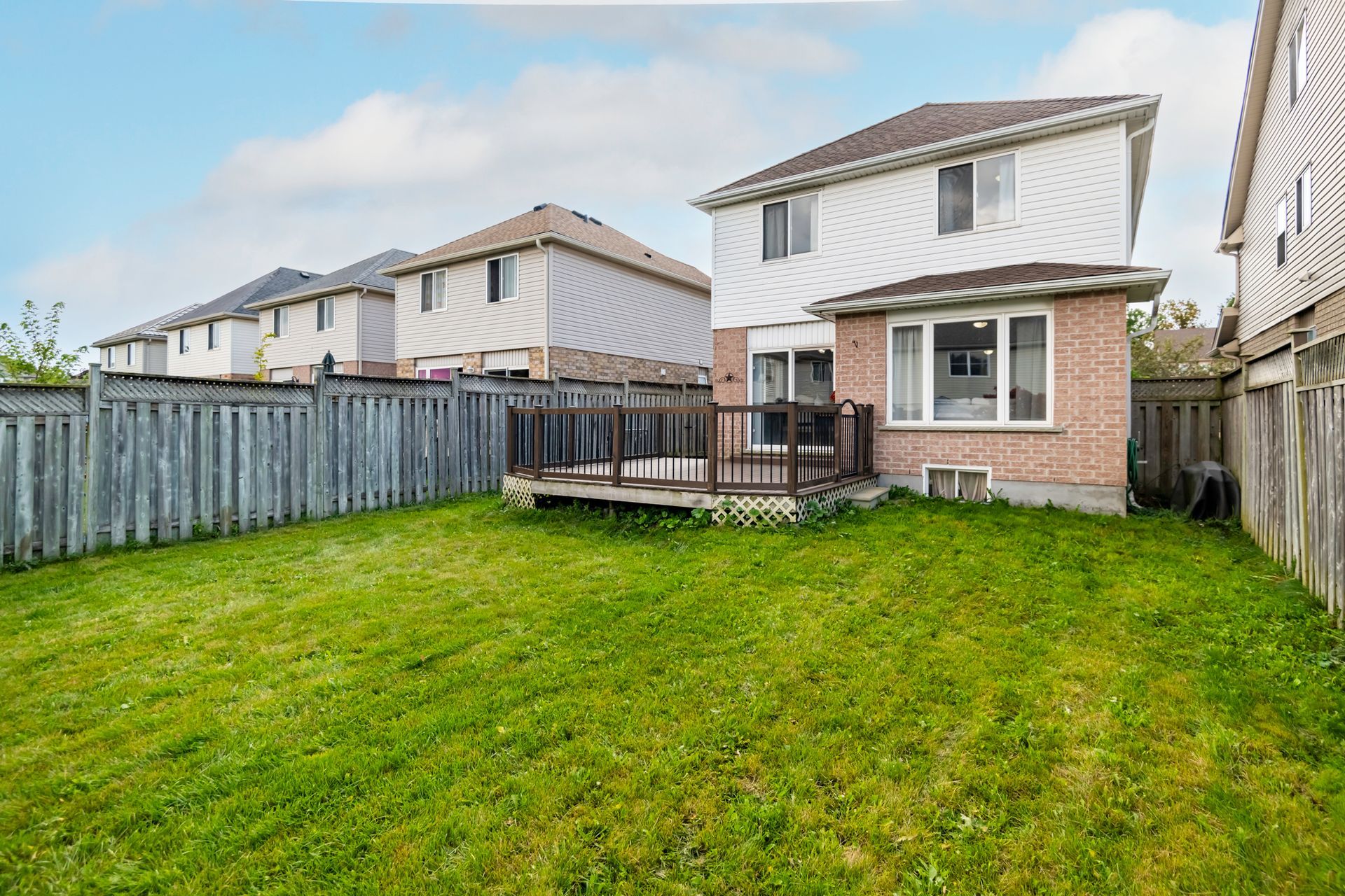 The backyard of a house with a large lawn and a deck.
