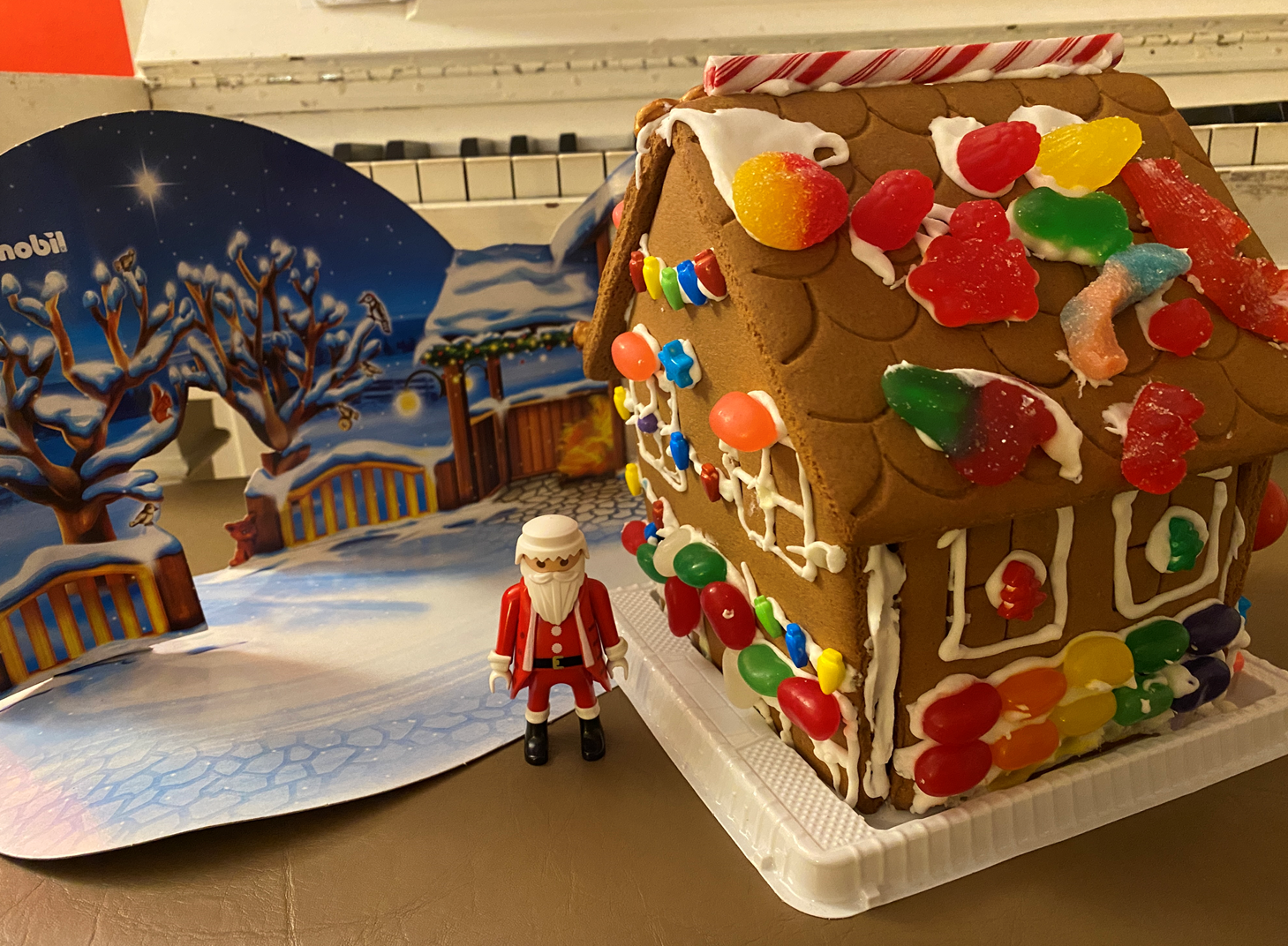 A gingerbread house with candy and a santa figurine next to it