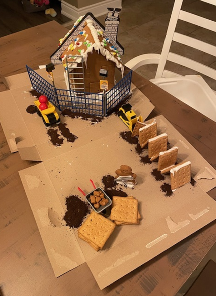 A gingerbread house is sitting on top of a cardboard box on a table.