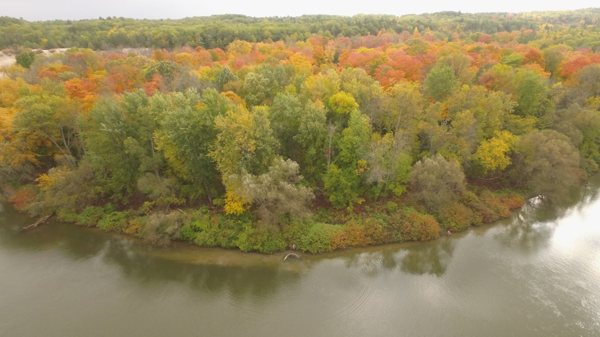 An aerial view of a lake surrounded by trees in autumn.