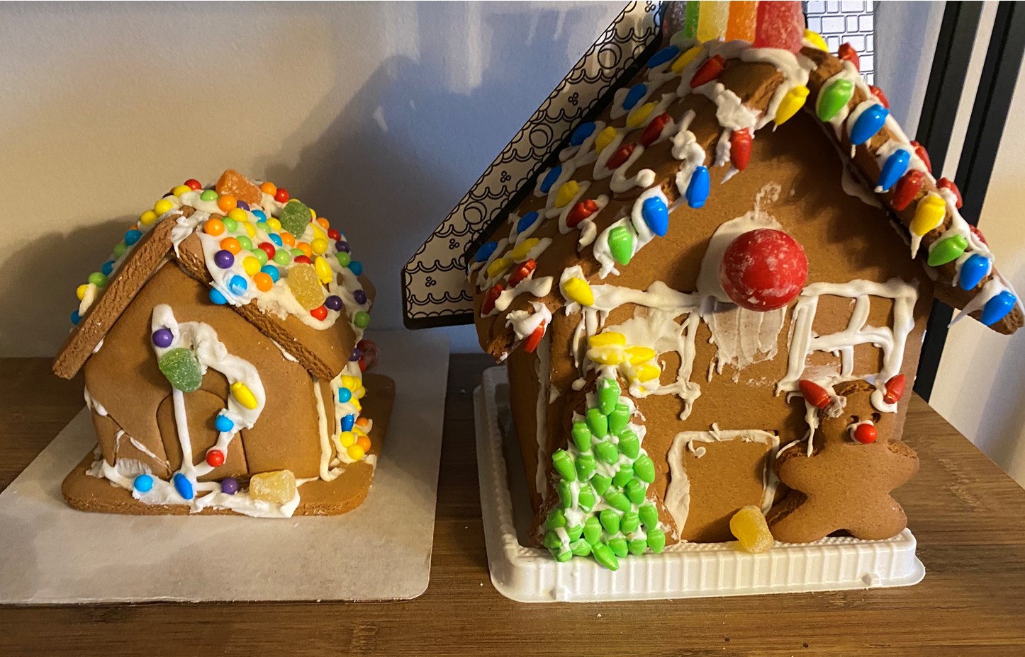 Two gingerbread houses are sitting on a wooden table.
