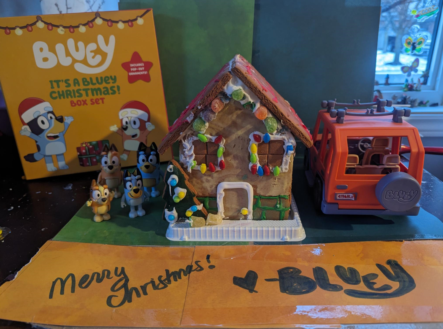 A gingerbread house and a toy truck are on a table.