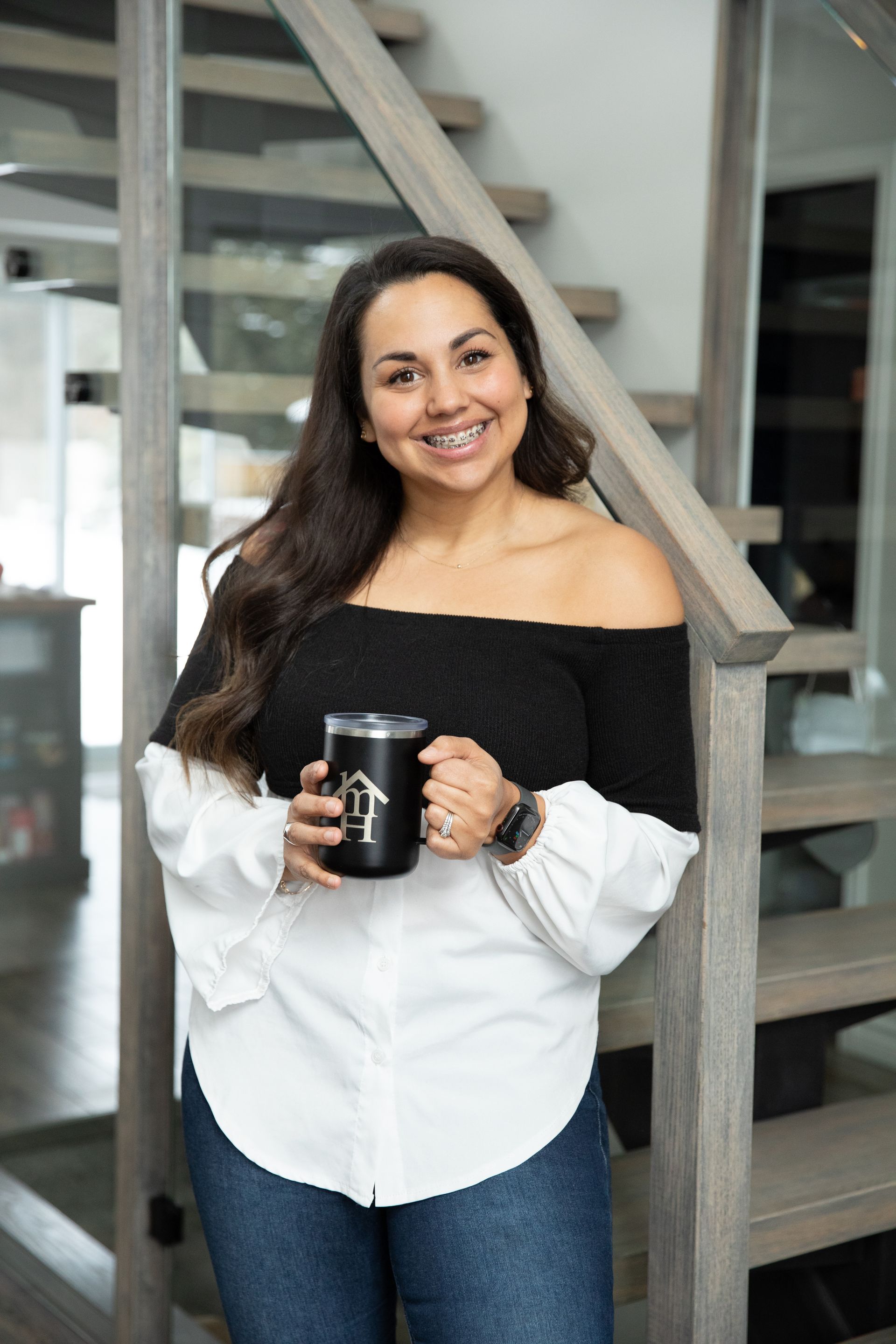 A woman is standing on a set of stairs holding a cup of coffee.