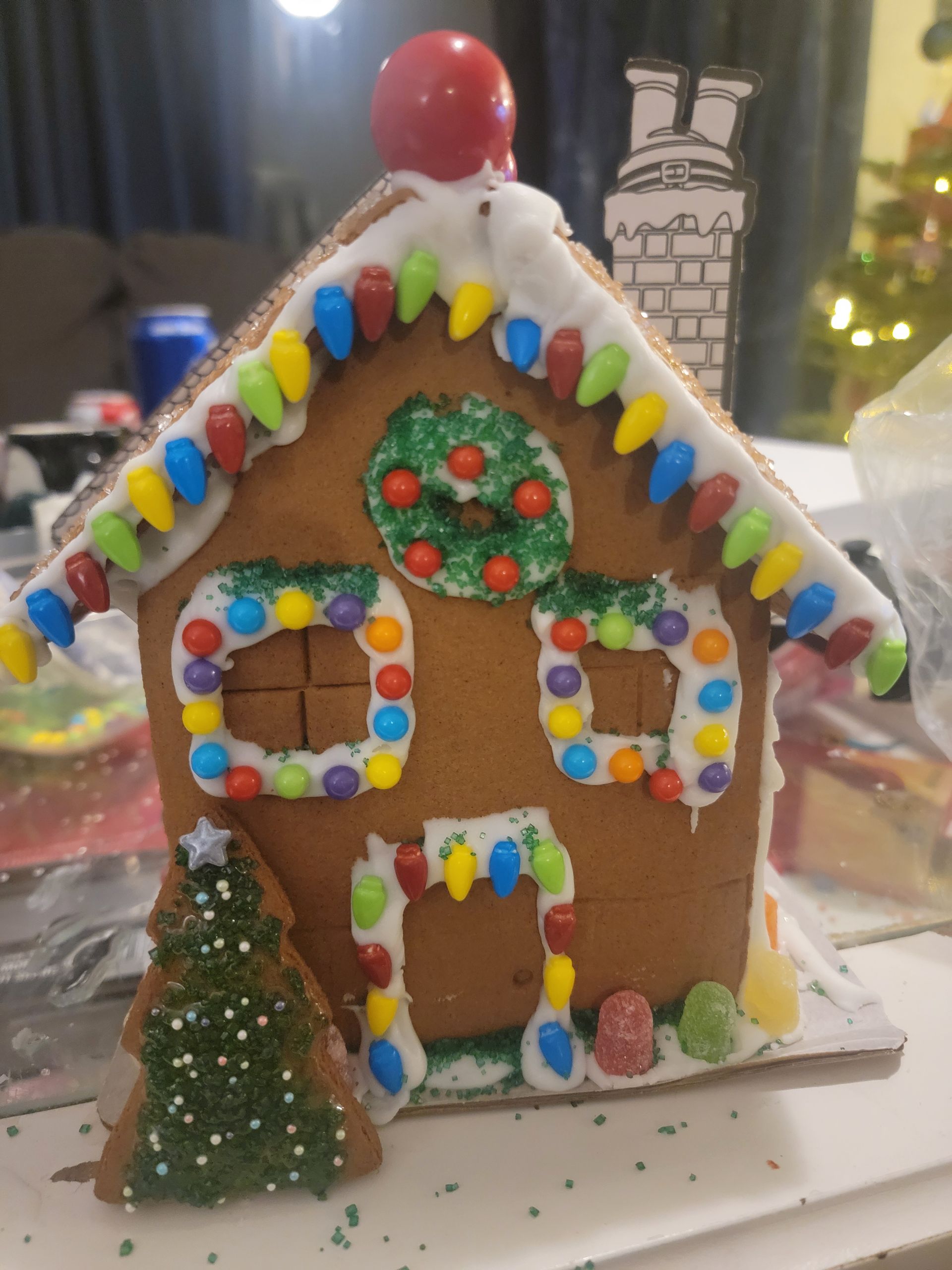A decorated gingerbread house with a christmas tree in front of it