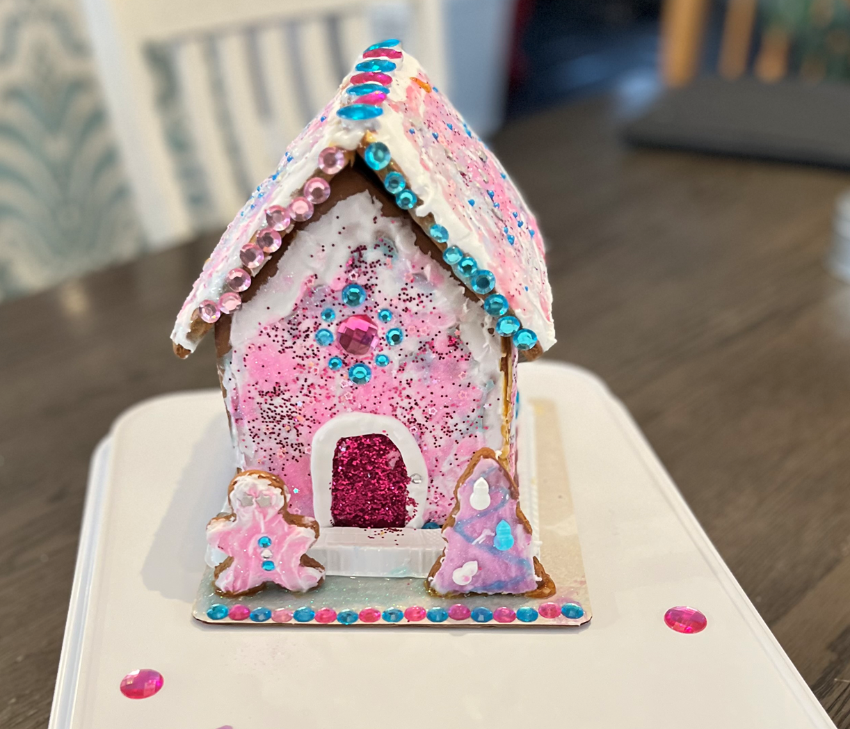 A pink gingerbread house is sitting on a white tray
