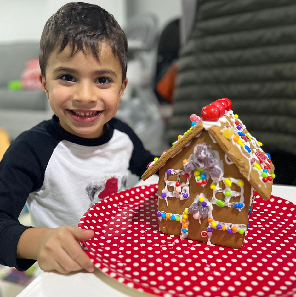 A young boy is holding a plate with a gingerbread house on it