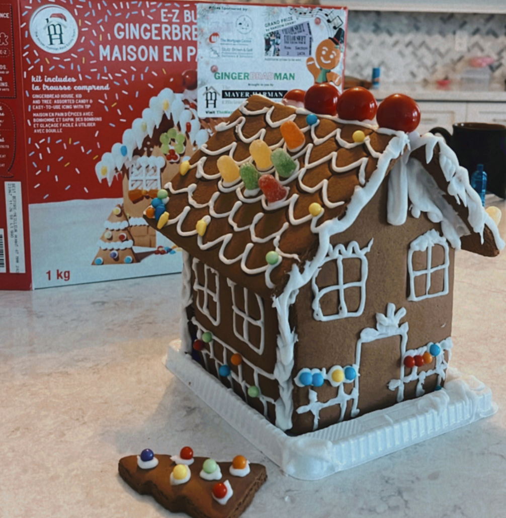 A gingerbread house sits on a counter next to a box of gingerbread