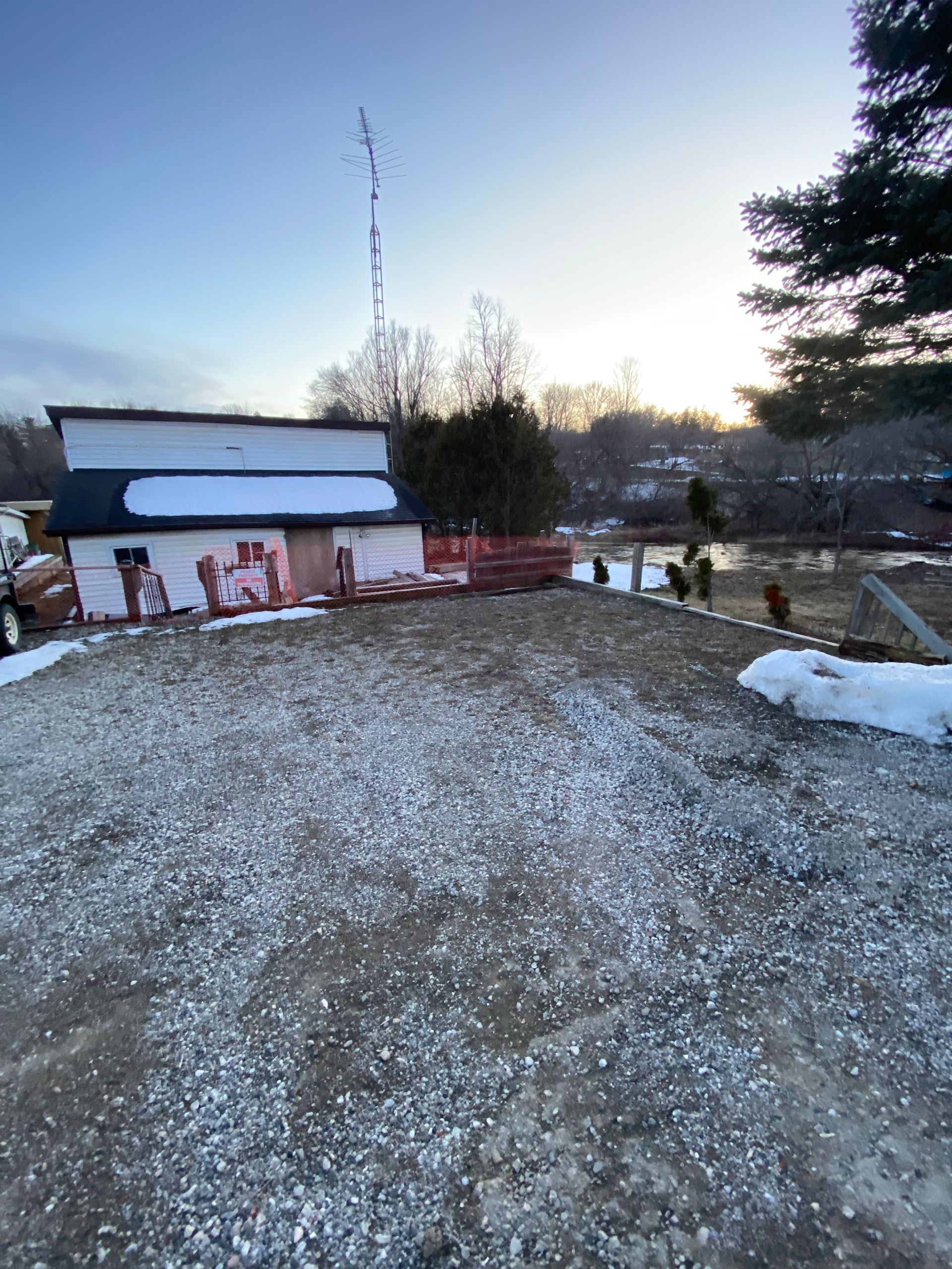 A gravel road leading to a building in the snow.