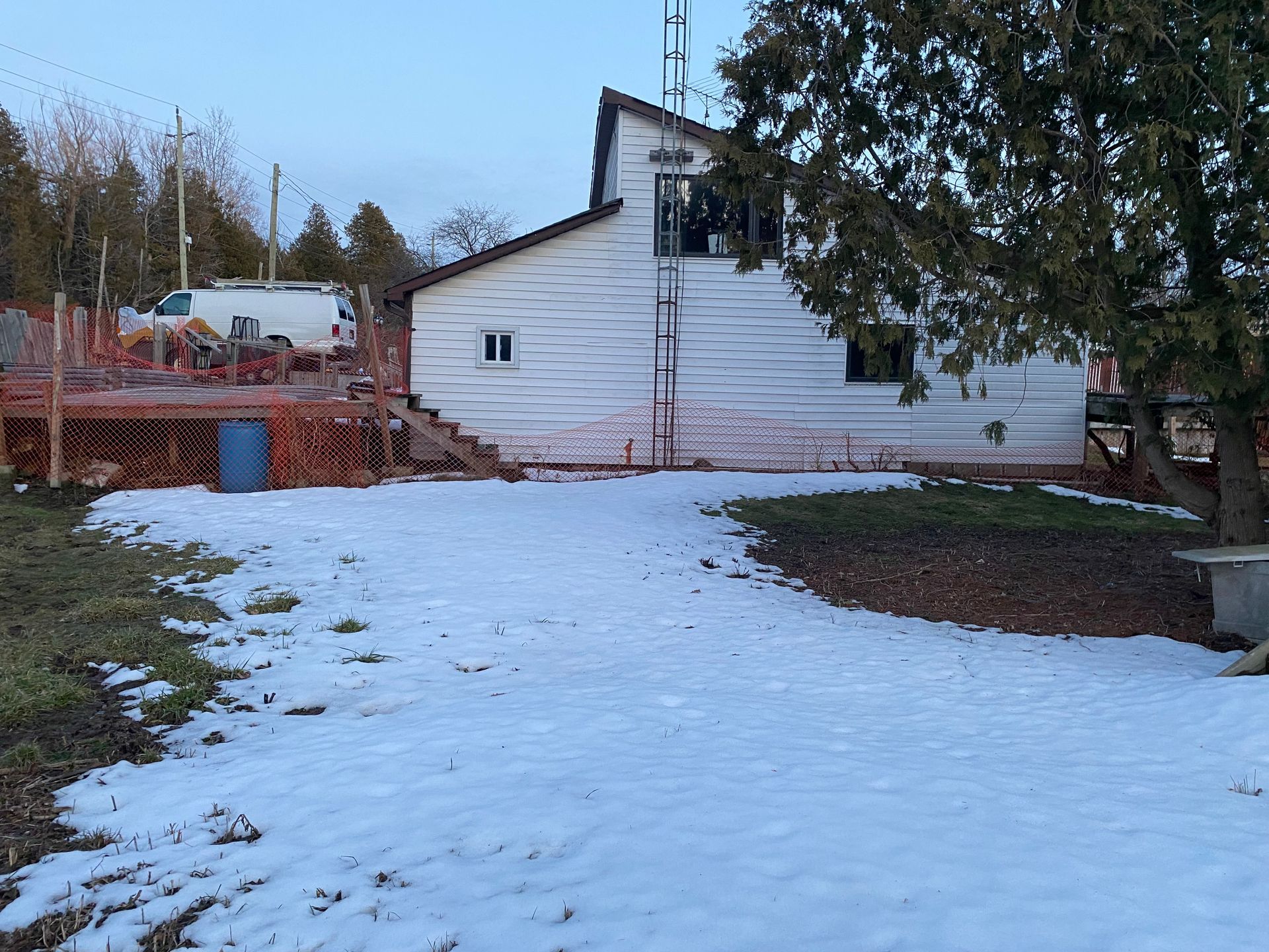 A snowy yard with a house in the background