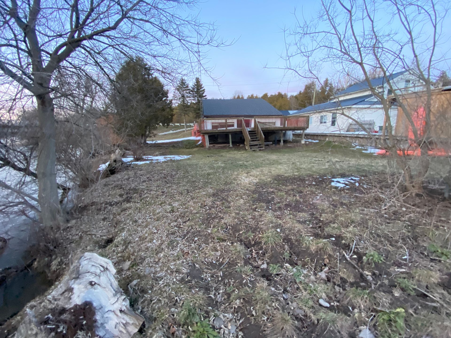 A house is sitting on top of a dirt hill next to a body of water.