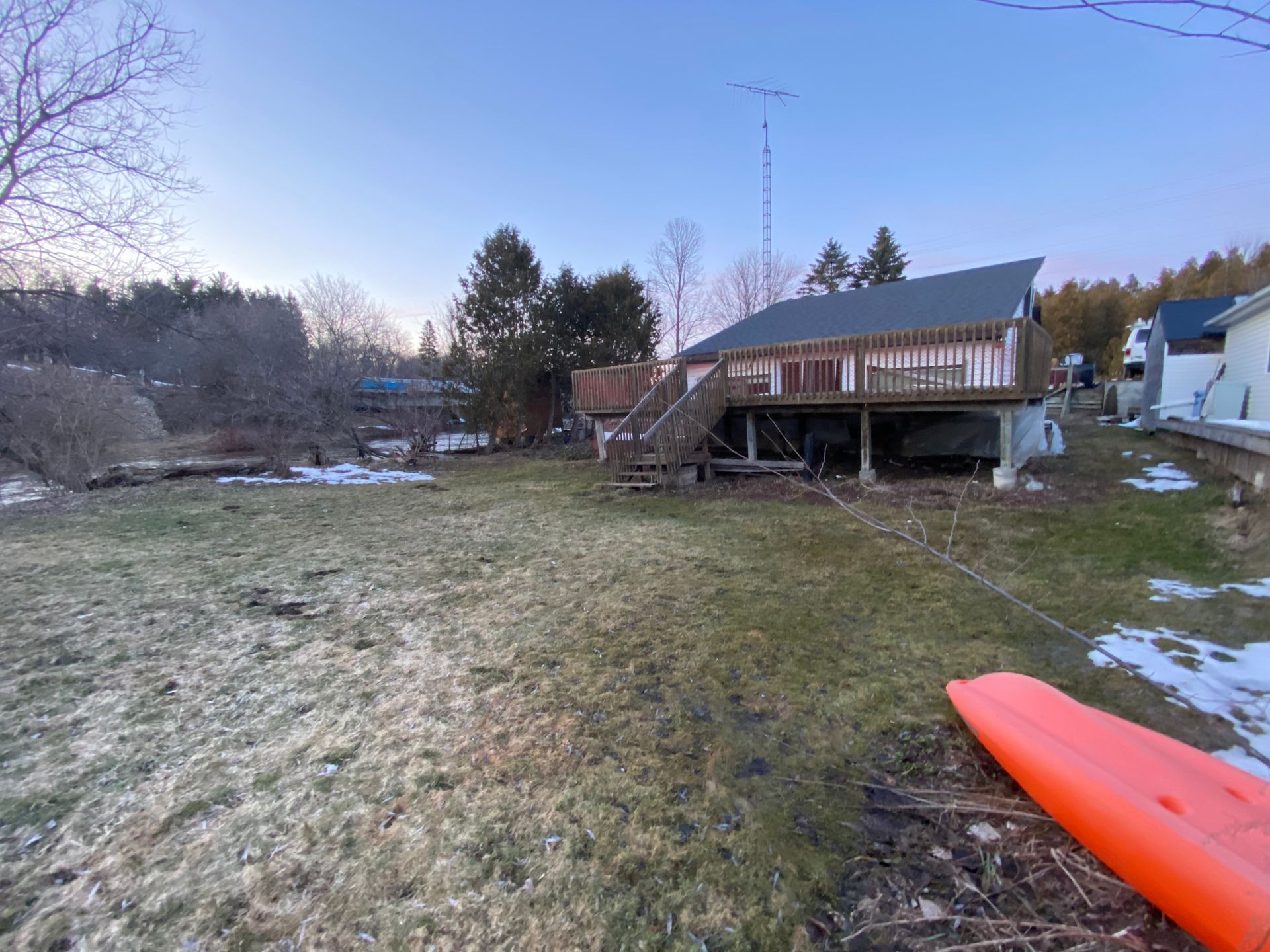 An orange kayak is sitting in front of a house under construction.