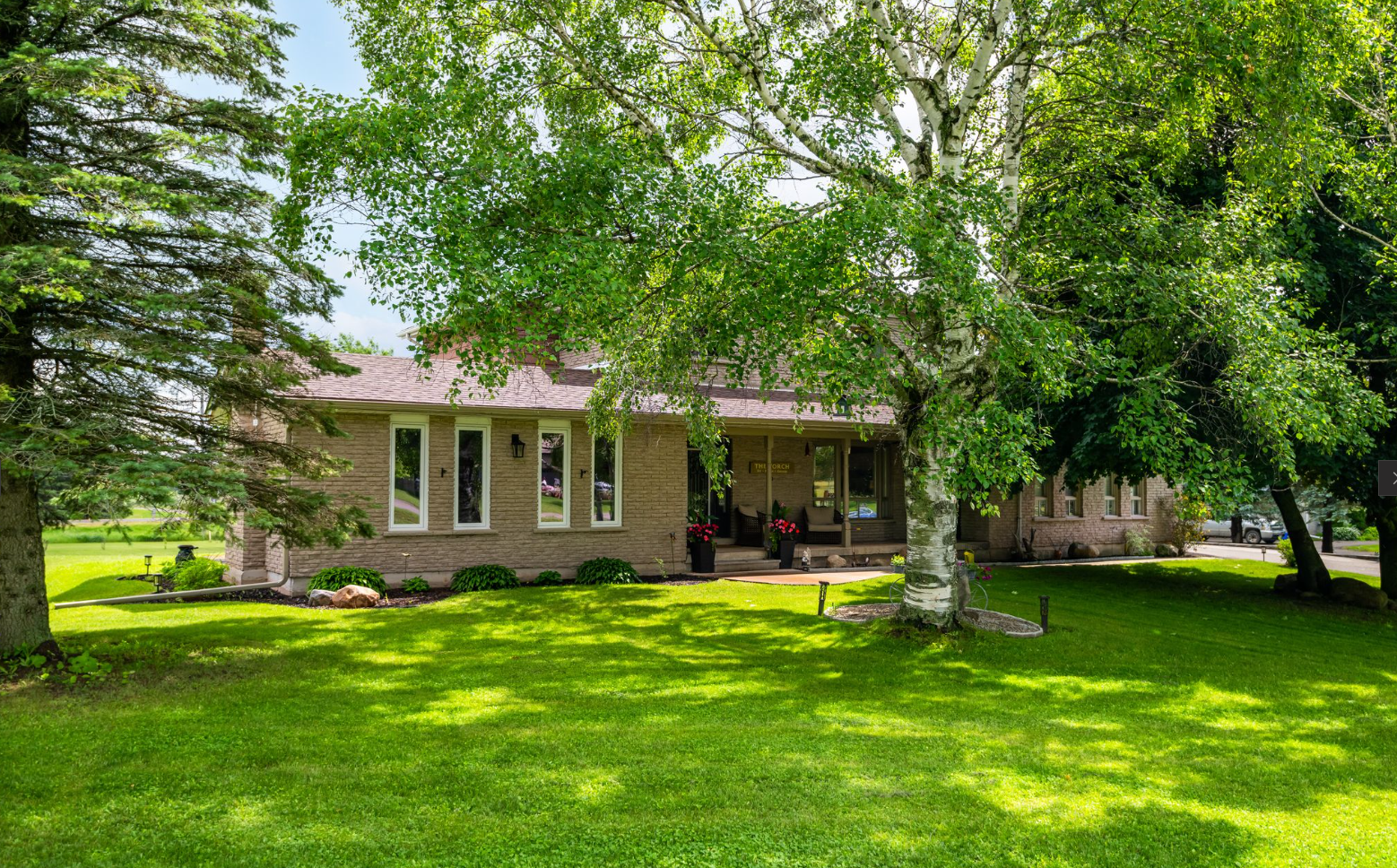 A house with a large lawn and trees in front of it.
