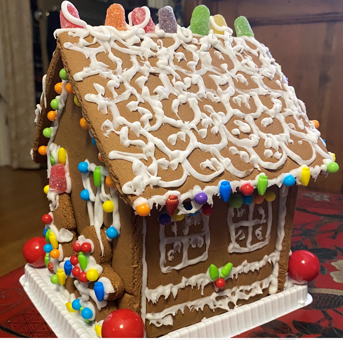 A gingerbread house is decorated with white frosting and candy