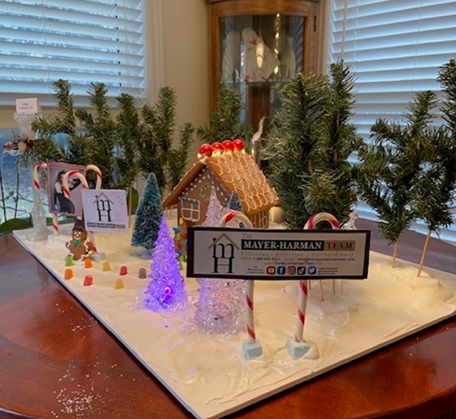 A model of a gingerbread house with candy canes and trees on a table.
