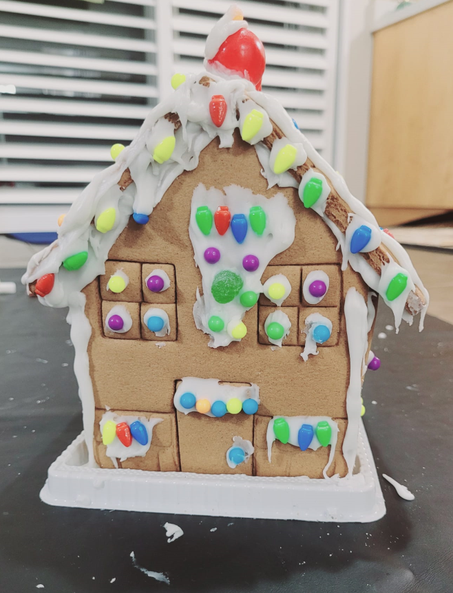 A gingerbread house with white frosting and colorful sprinkles