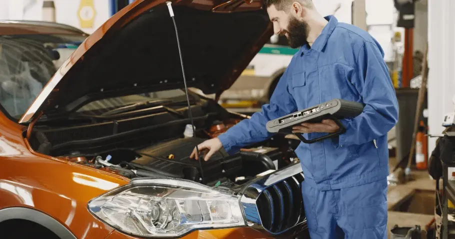 Mechanic using a diagnostic tablet to scan a car engine.