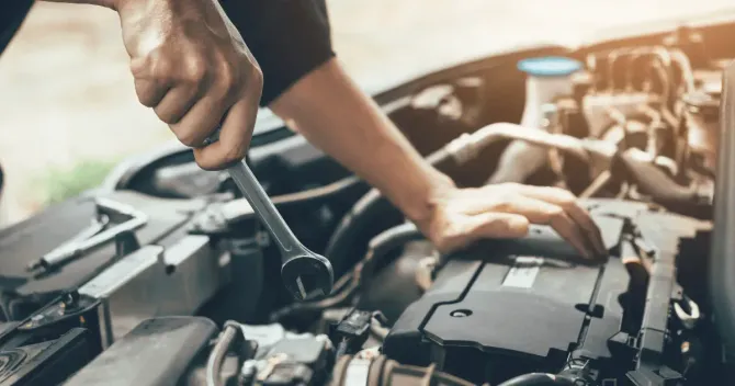 Mechanic using a wrench to repair a car engine.