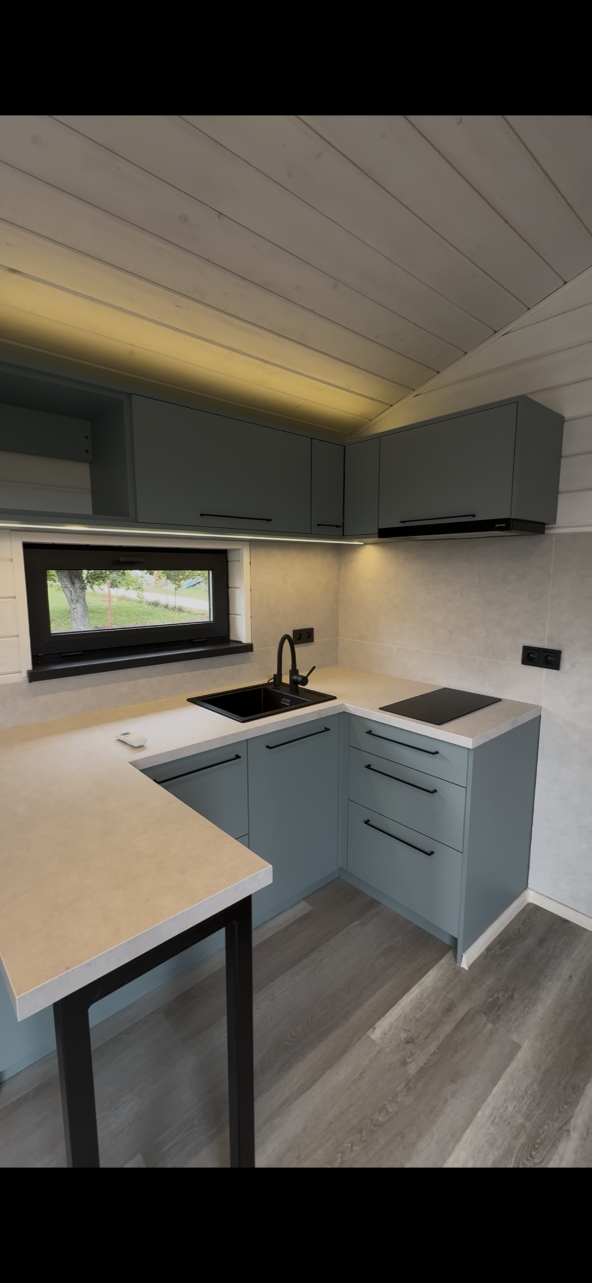 A small kitchen with light blue cabinets, a black sink and faucet, and a countertop.