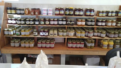Shelves of jars filled with preserves, jellies, and honey for sale in a shop.