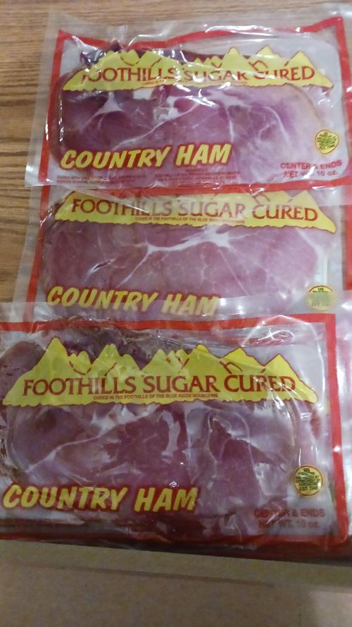 Three packages of Foothills Sugar Cured Country Ham. The ham is pink, packaged in clear plastic.
