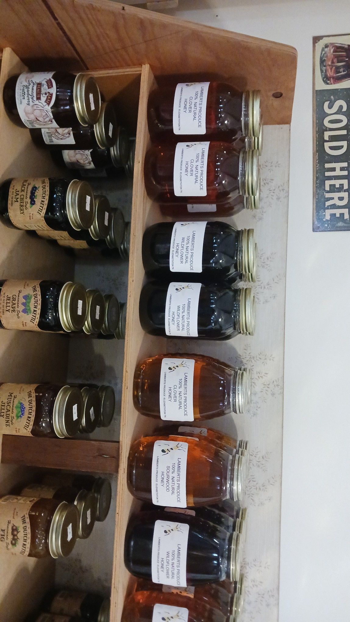 Shelves holding jars of honey for sale, various colors, with a 