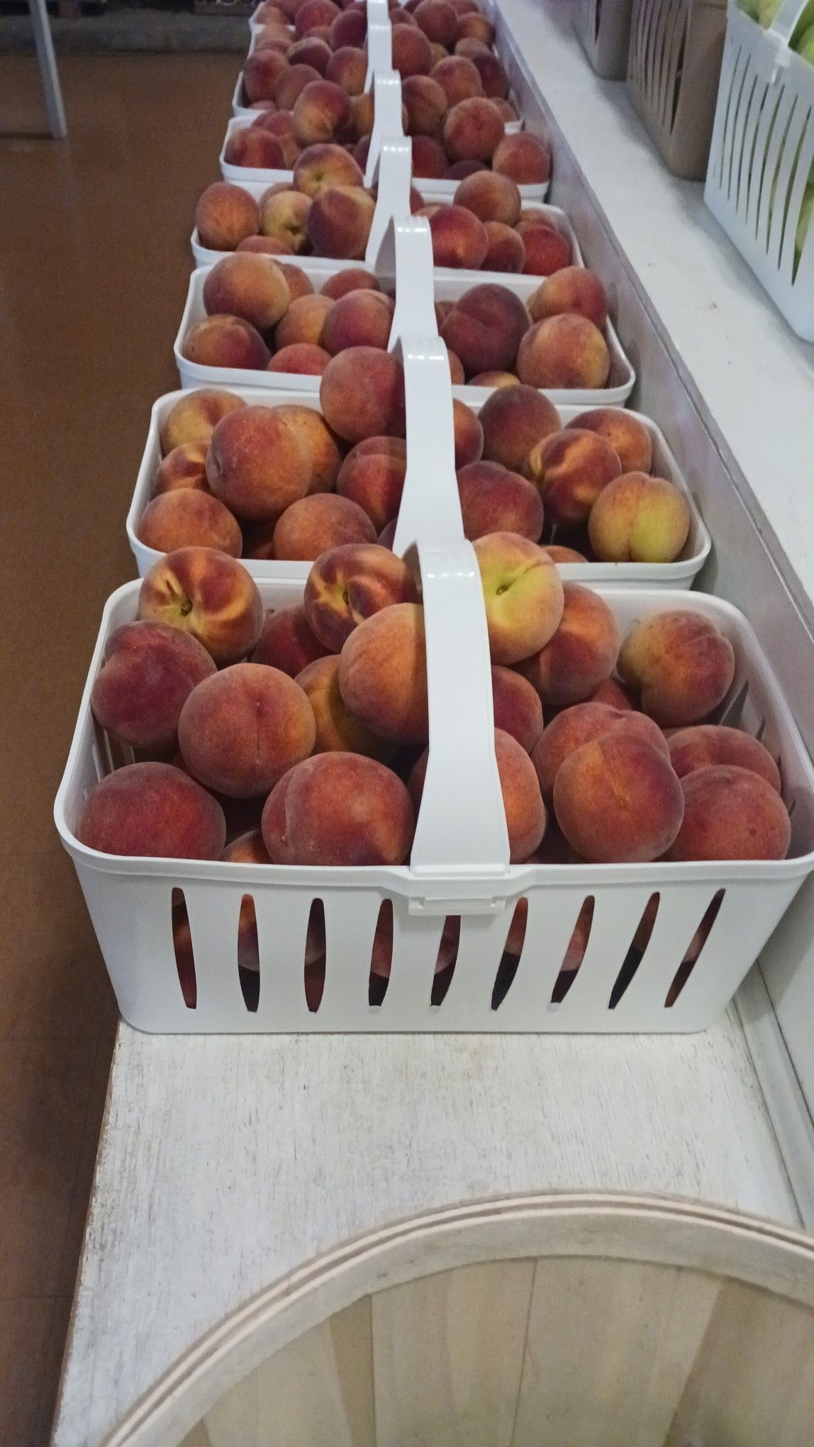 Baskets of fresh peaches sit on display in a market setting.