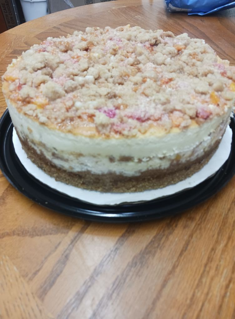 Cheesecake with a crumb topping, set on a black plate on a wooden table.