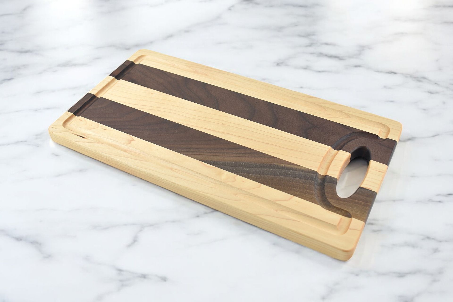A wooden cutting board with a handle on a marble surface